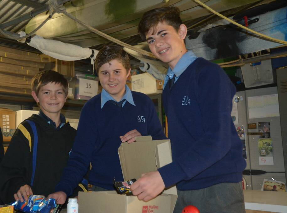 COMMITTED: Peter Connett, Brayden Forsyth and Logan Milton-Smith packing boxes bound for the Middle East.